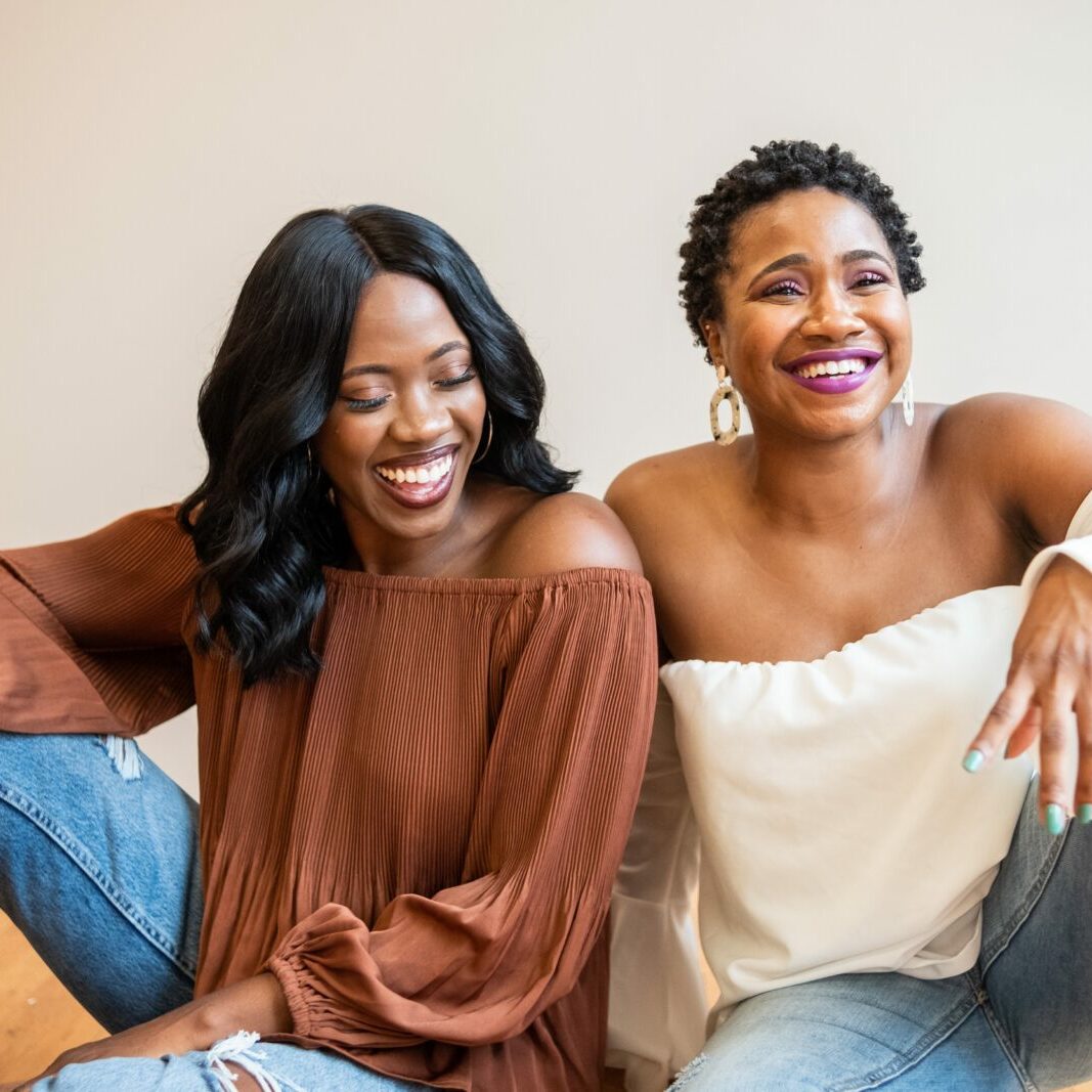 black women sit next to each other laughing