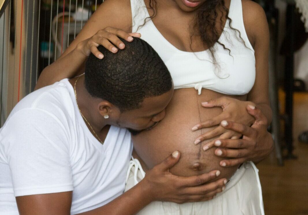 A man kisses a woman's pregnant belly