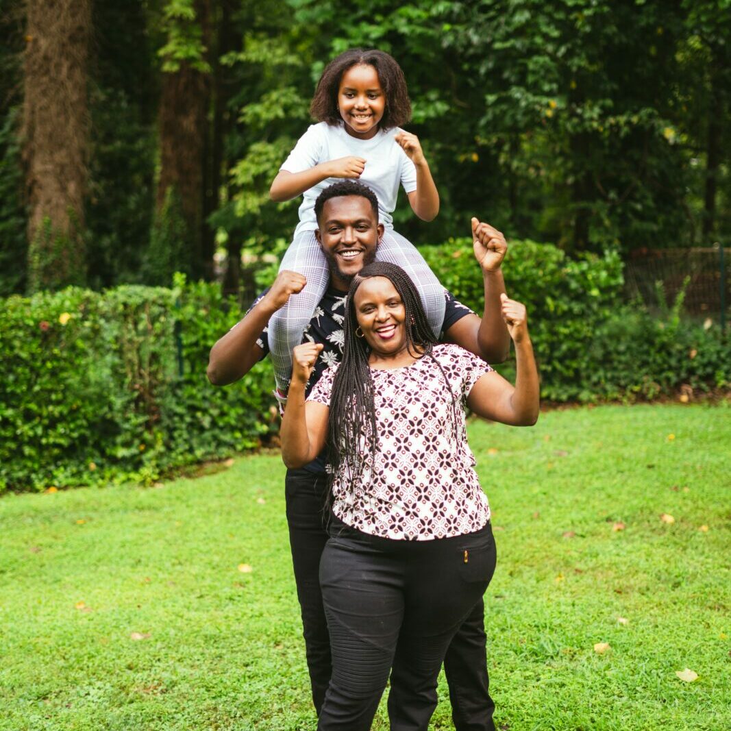 a happy black family stands in a green yard